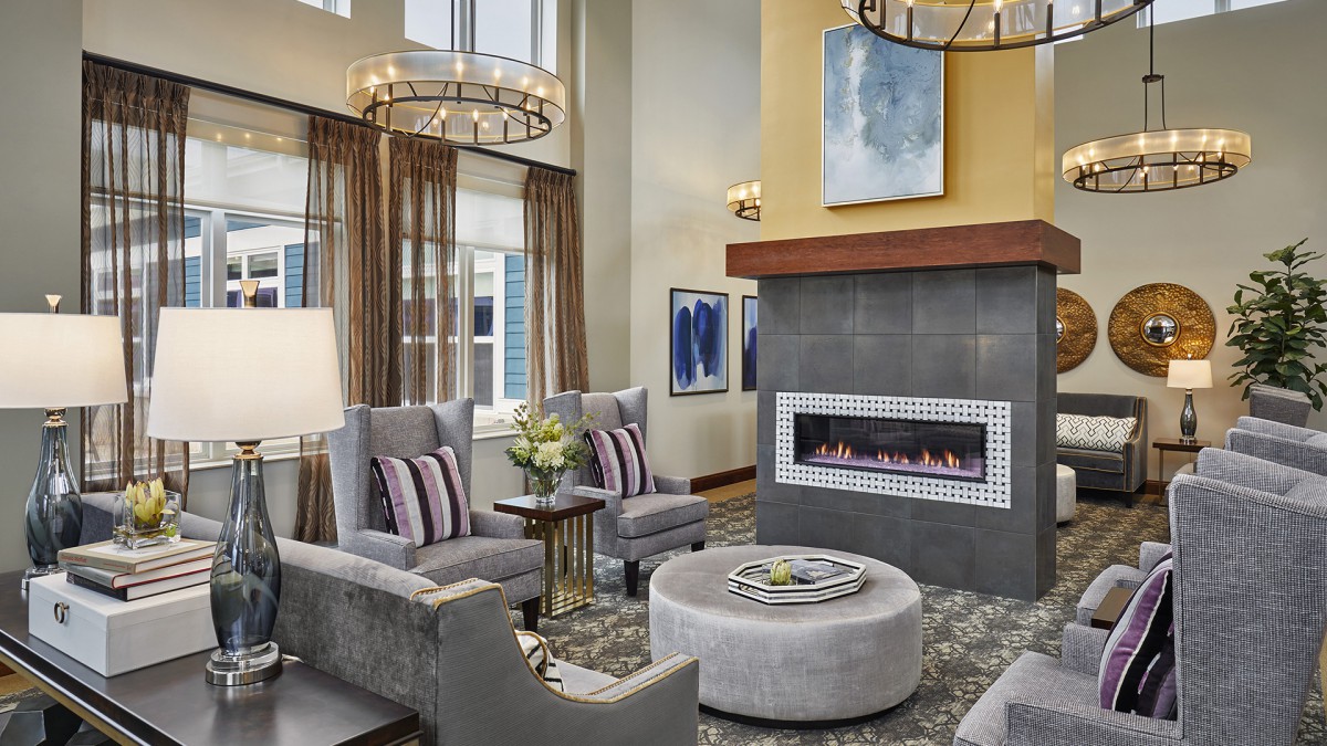 A modern living room featuring a sleek fireplace, elegant chandeliers, and contemporary seating arrangements.