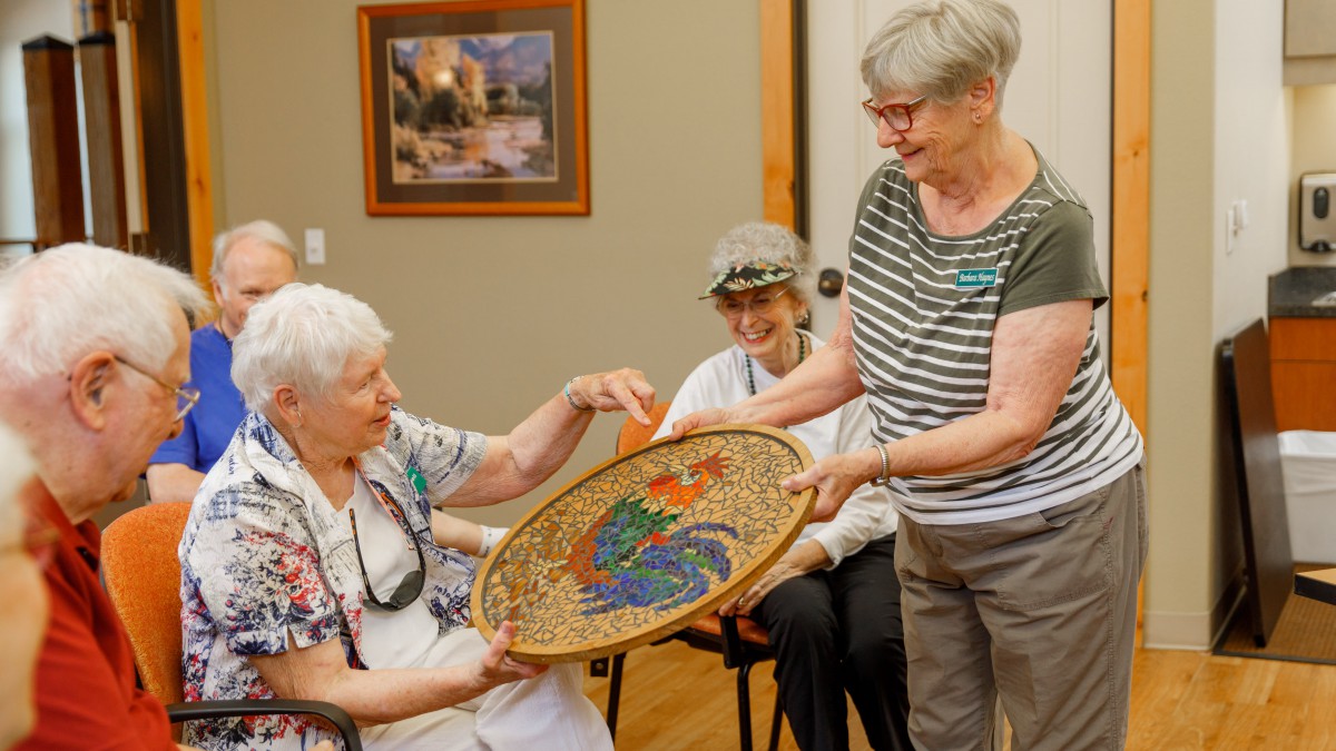 Elderly women sharing and admiring a colorful basket in an indoor setting.