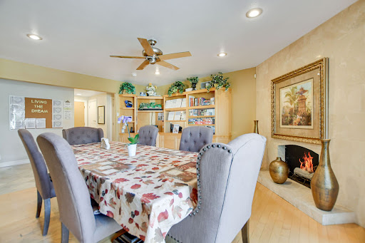 A cozy and well-decorated dining room featuring a large table, comfortable chairs, and shelves filled with books.