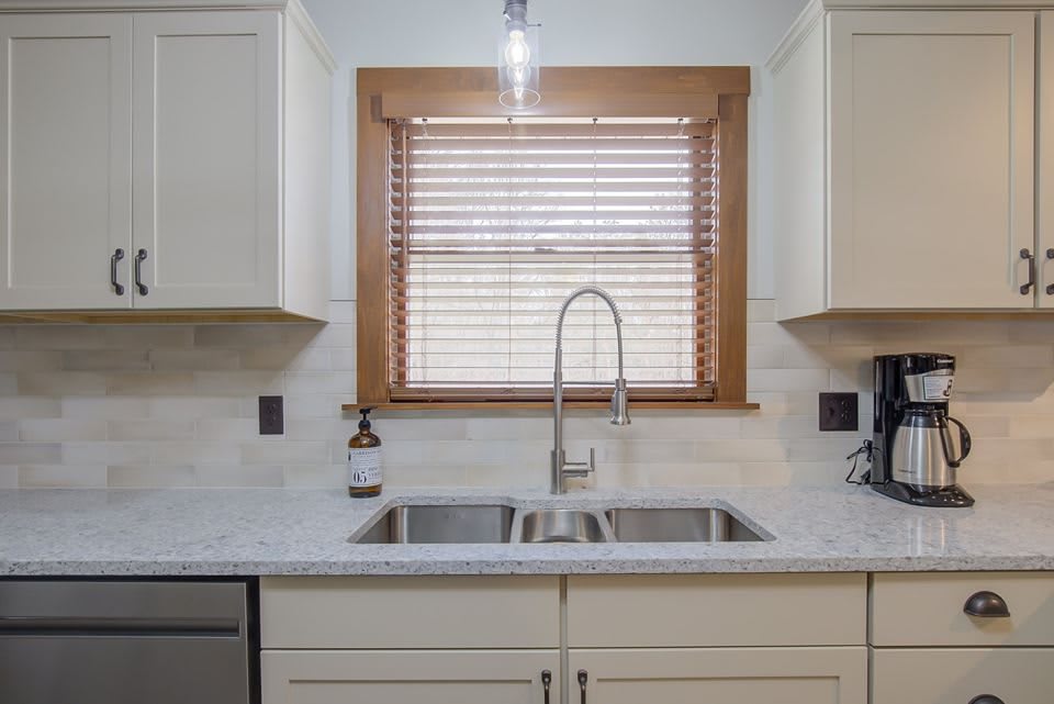 A modern kitchen with a dual sink and a window with wooden blinds.