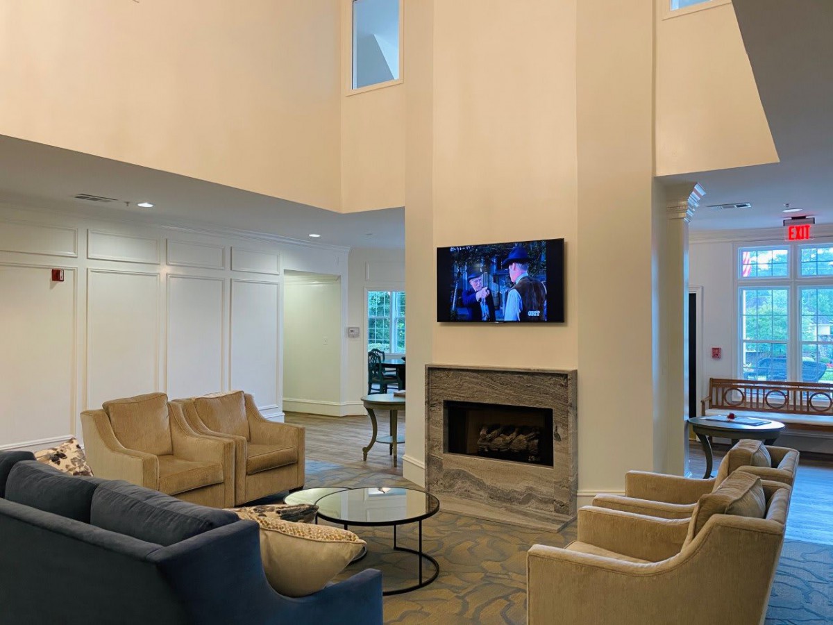 A spacious modern living room with comfortable seating, a fireplace, and a wall-mounted television.