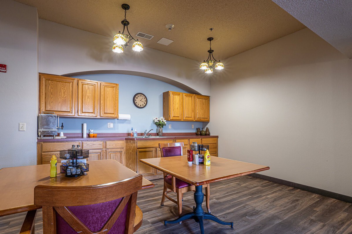 A cozy kitchen and dining area with wooden cabinets, tables, and chairs.