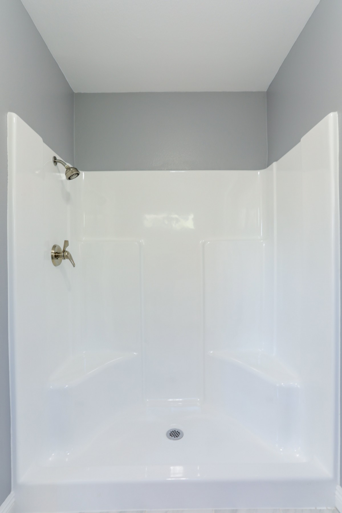 A clean and minimalist bathroom shower with white walls.