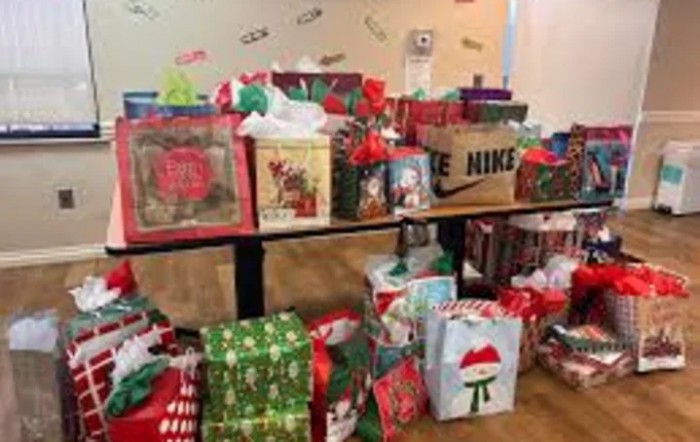 A collection of festive Christmas gifts wrapped in colorful paper and bags, arranged on a table.