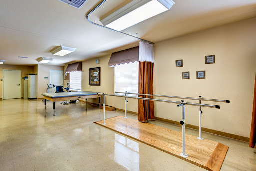 A well-lit physical therapy room featuring a ballet bar and an exercise table, designed for rehabilitation activities.