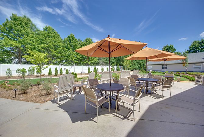 A sunny outdoor patio area with tables, chairs, and umbrellas set up for relaxation.