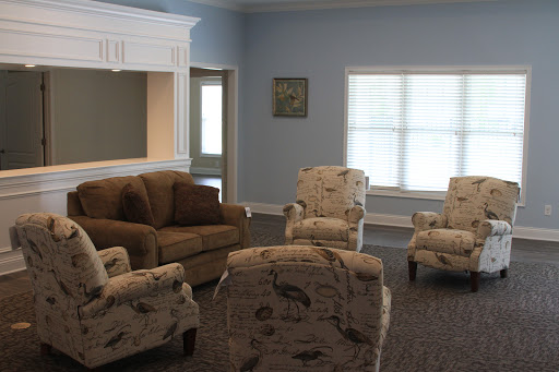 A cozy living room setup featuring a brown sofa and patterned chairs, illuminated by natural light.
