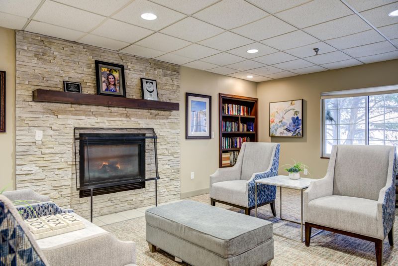 A cozy living room with a fireplace, comfortable seating, and a bookshelf.