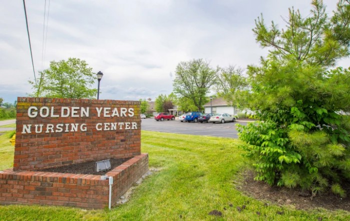 Entrance sign of a nursing center surrounded by greenery and a parking lot.