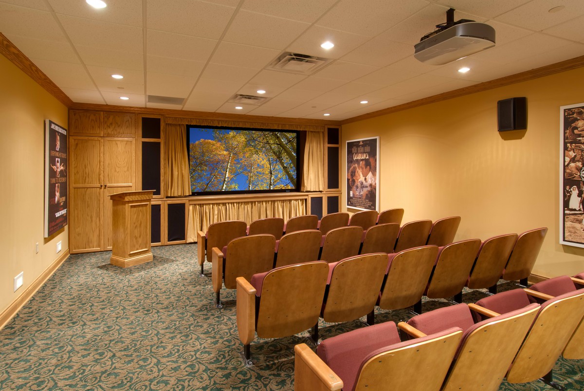 A cozy home theater room with rows of seating, a large screen, and a projector for viewing movies.