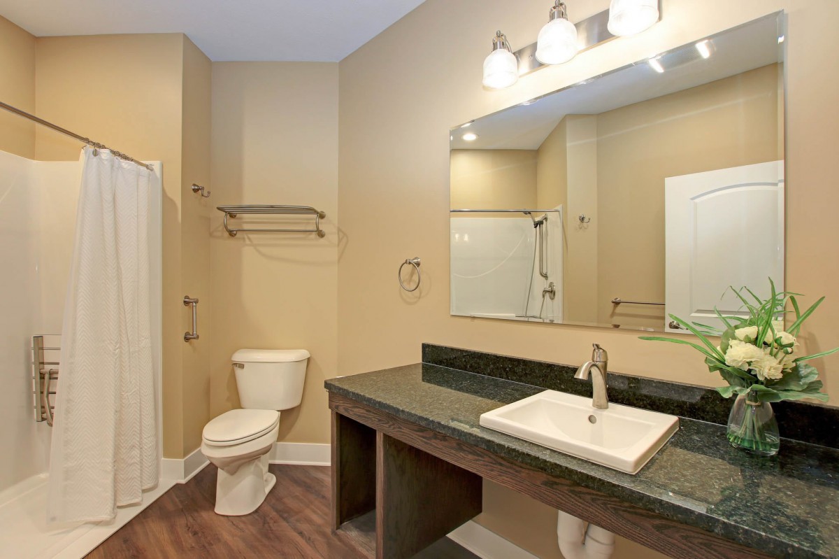 A modern bathroom with a spacious countertop, sink, mirror, and lighting.