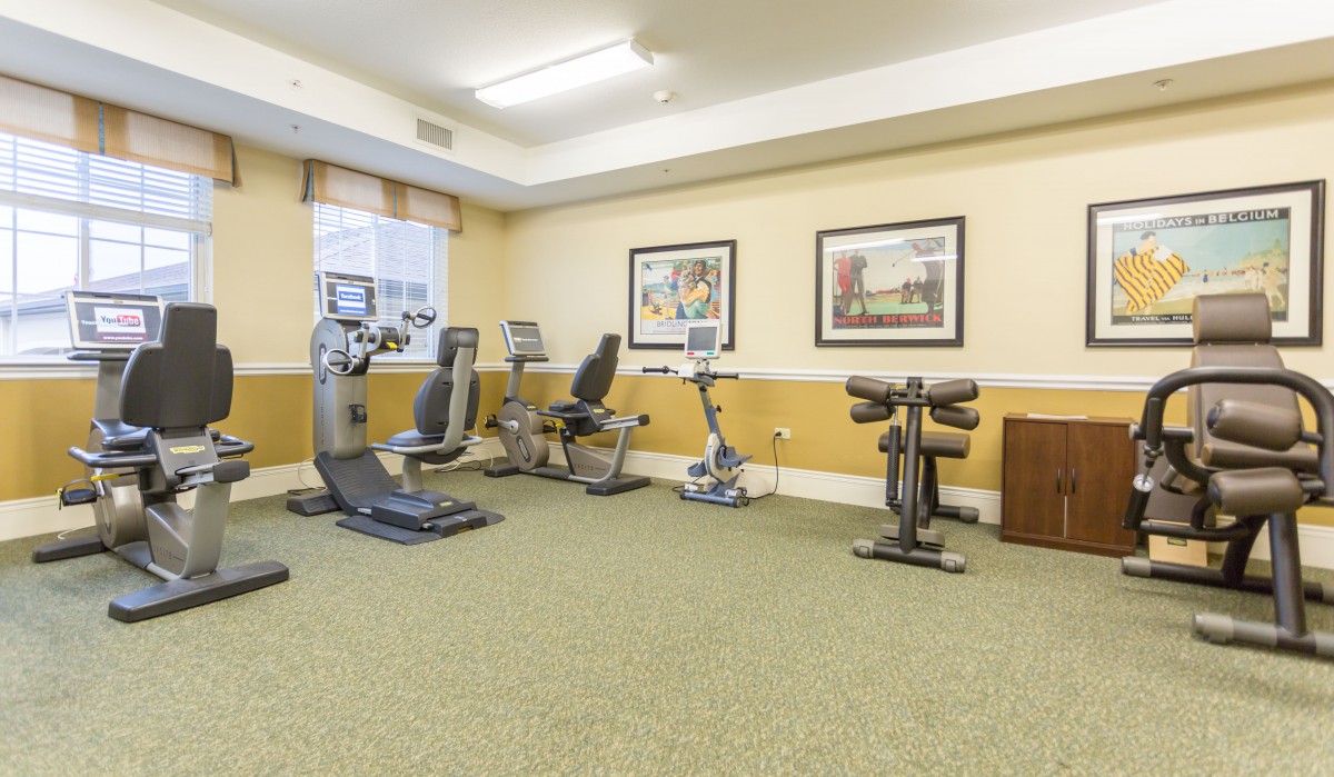 A small indoor gym with various exercise equipment and framed artwork on the walls.