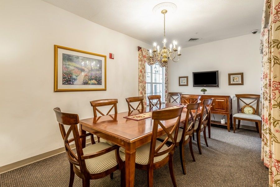 A well-furnished dining room with a long wooden table, chairs, a chandelier, and artwork on the walls.