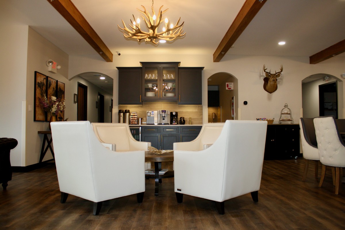 A stylish living room with white armchairs, a unique antler chandelier, and modern design elements.
