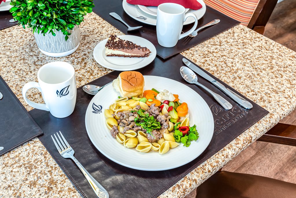 A well-presented meal with pasta, salad, and dessert on a dining table.