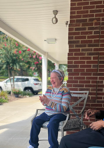 A joyful elderly woman enjoying a sunny day on her porch.