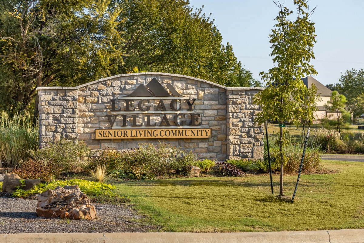 Entrance sign for a senior living community surrounded by greenery.