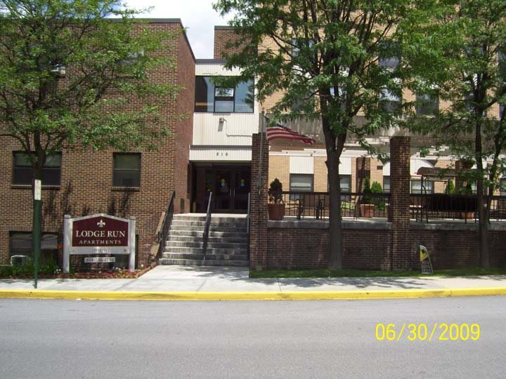 A brick building with an entrance and stairs, surrounded by trees.