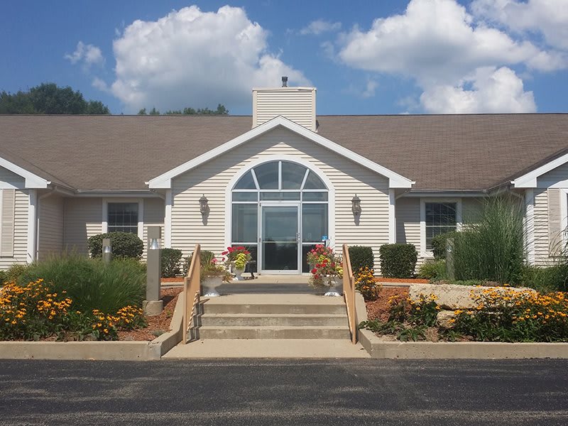 A front view of a building with a large arched window, surrounded by landscaping and set against a cloudy sky.