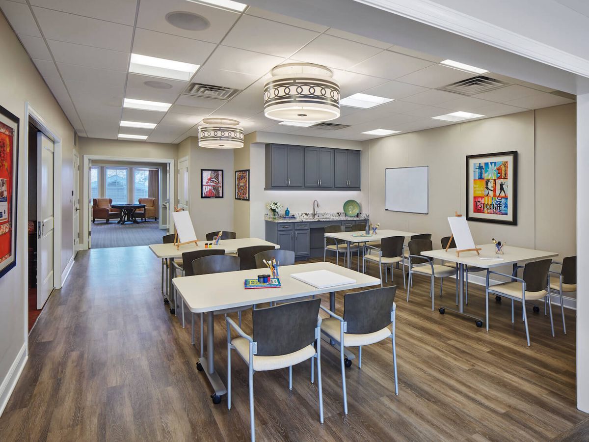 A modern conference room with tables and chairs, featuring stylish overhead lighting and wood flooring.