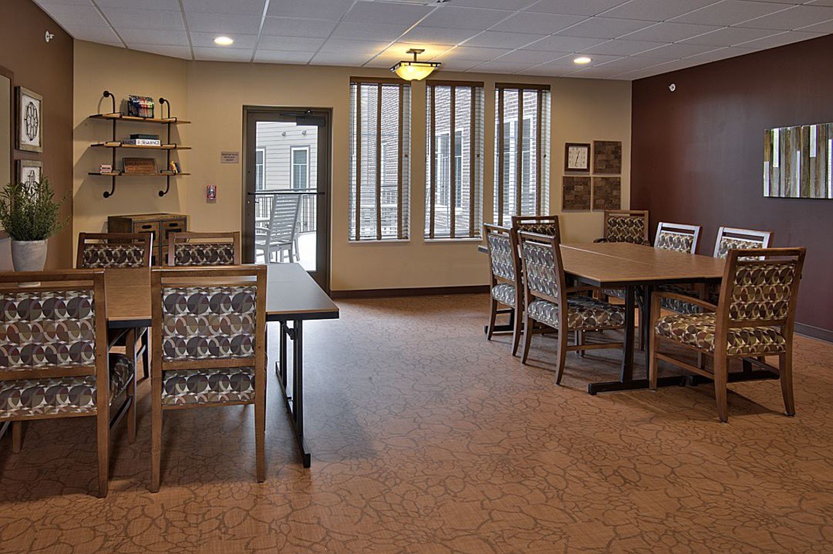 A well-lit dining room with tables and chairs, featuring large windows and modern lighting.