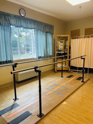 A physical therapy room featuring parallel bars for rehabilitation exercises.