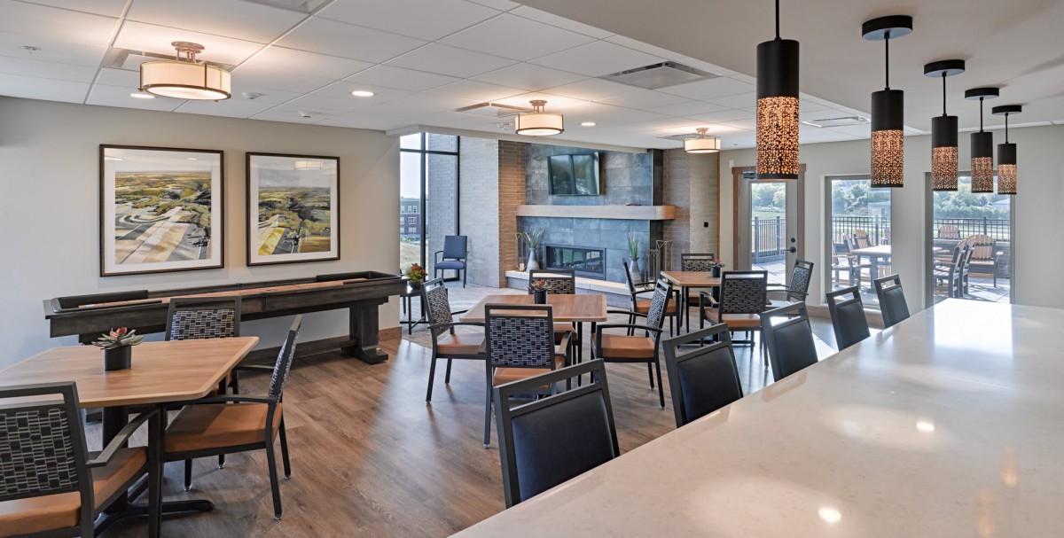 A modern lounge area featuring comfortable seating, a fireplace, and large windows.