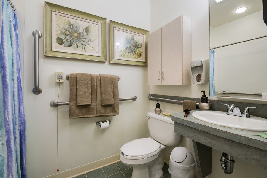 A clean and well-organized bathroom with towels hanging on the wall and decorative artwork above them.