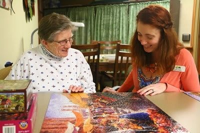 Two women enjoying completing a puzzle together indoors.