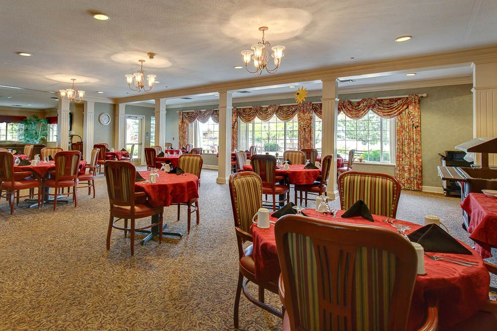 Elegant dining area with tables and chairs, featuring large windows and chandeliers.