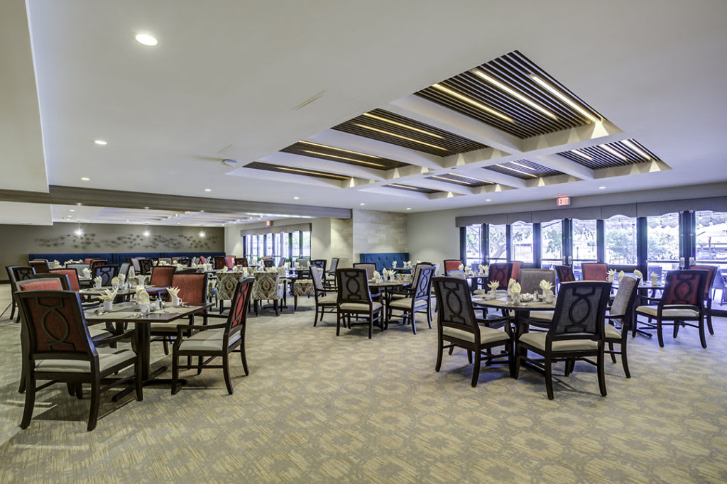 A spacious and elegantly decorated dining area with arranged tables and chairs, featuring modern ceiling designs.