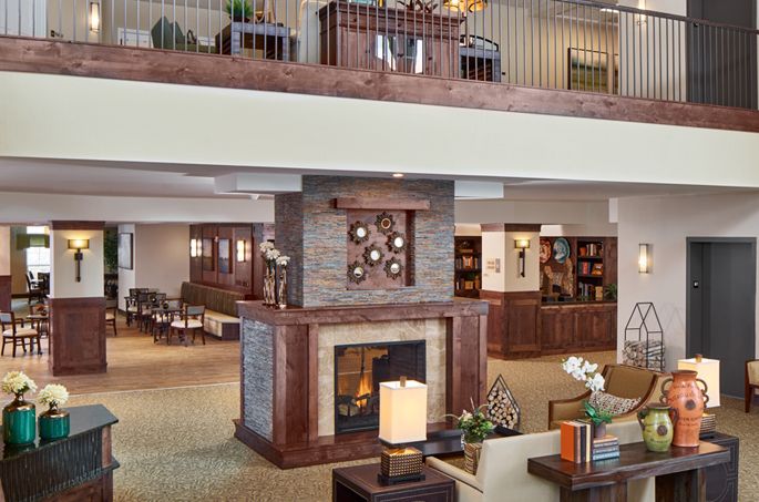 A modern lobby area with a central fireplace, elegant furniture, and open balcony.