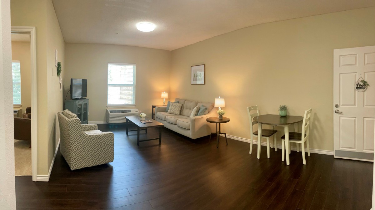 A cozy living room with a sofa, coffee table, and dining area.
