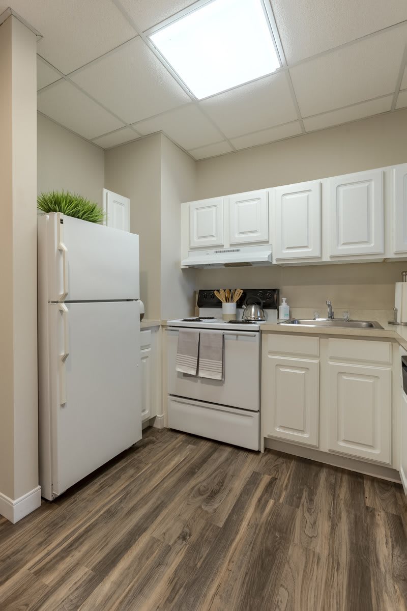 A small kitchen with white cabinetry, a refrigerator, and a stove.