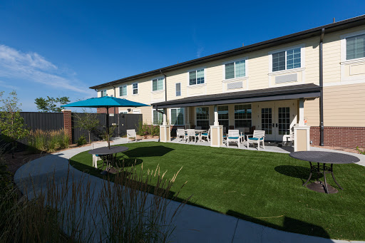 A modern two-story building with a well-maintained garden and outdoor seating area.