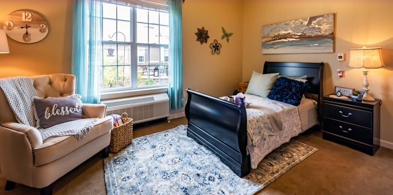 A cozy bedroom with a large window, single bed, and decorative elements.