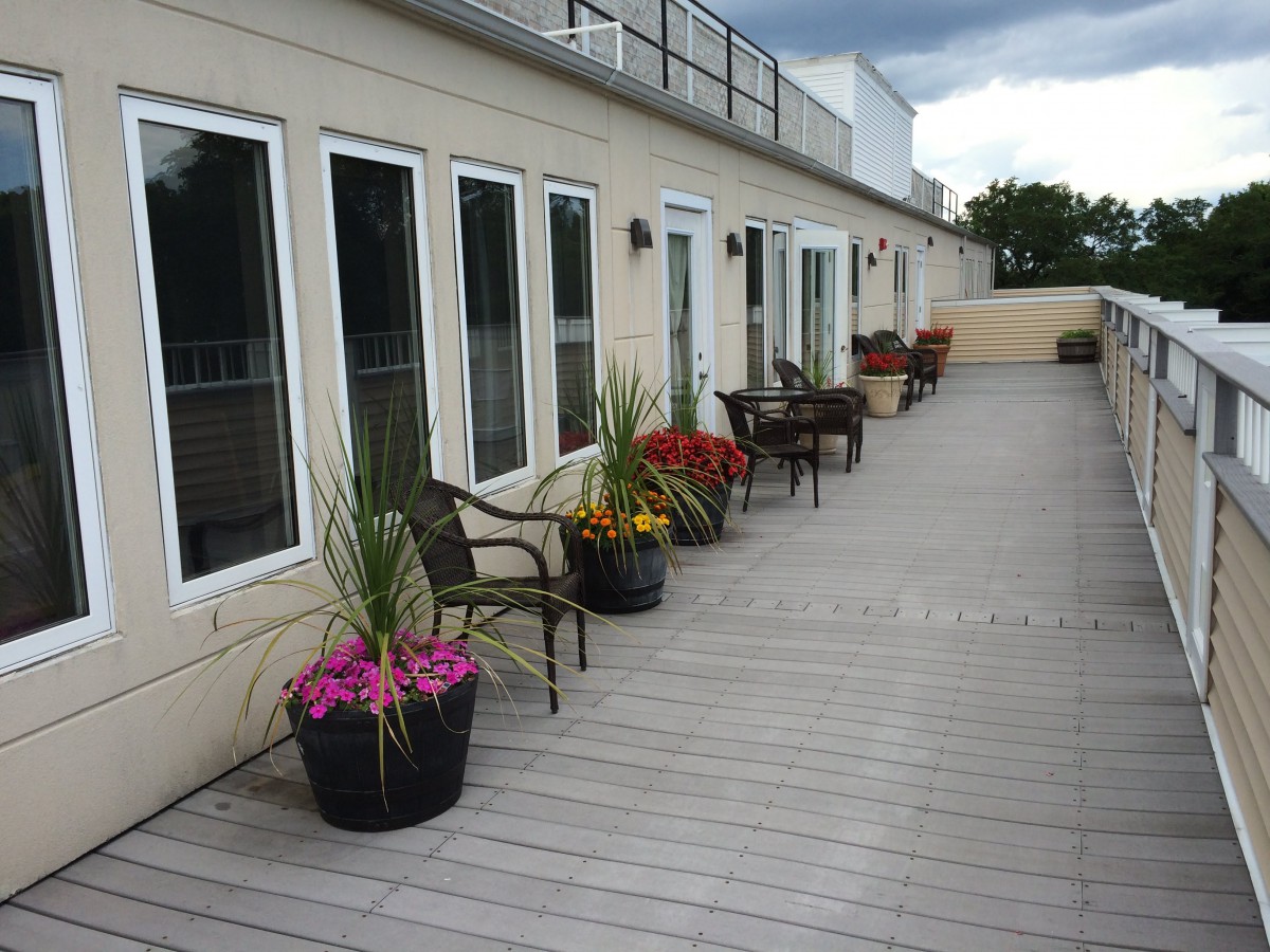 A spacious outdoor deck with seating and potted plants along the building exterior.