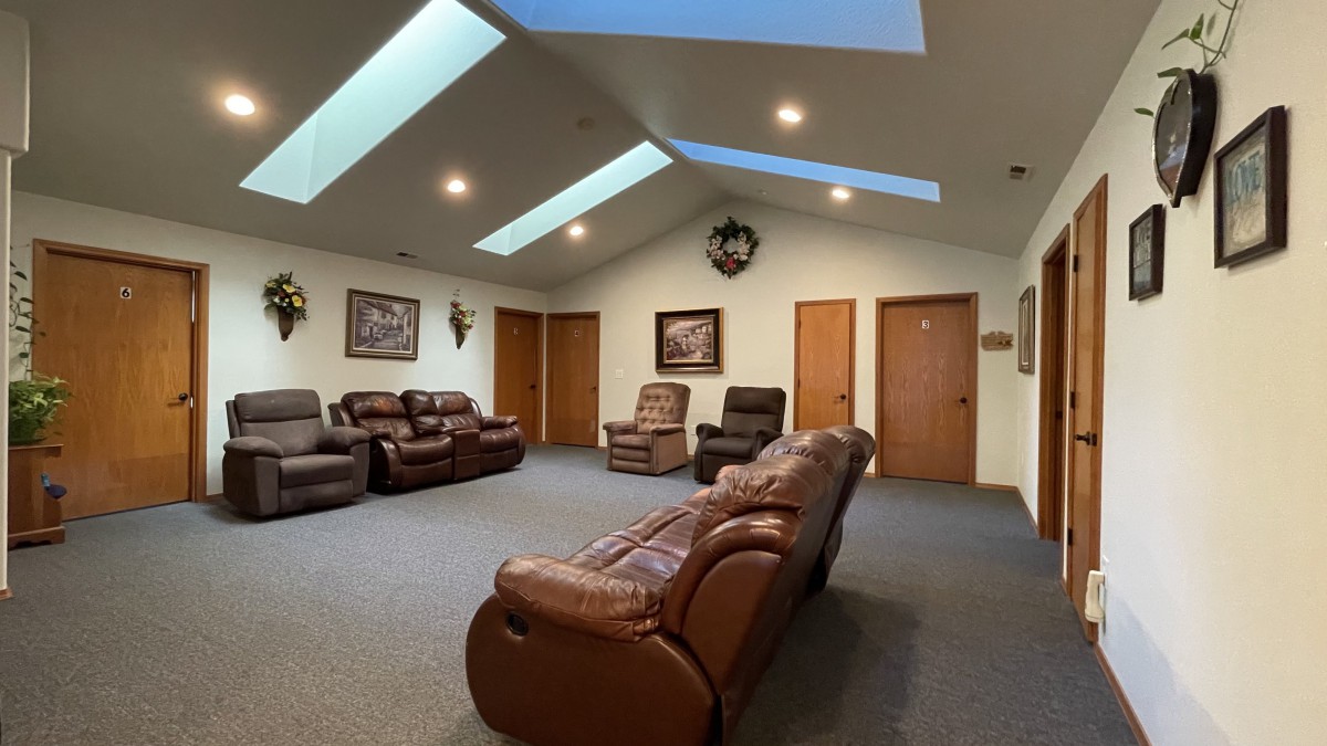 A spacious living room with multiple recliner sofas and ample natural light from skylights.