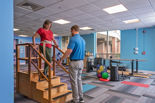 A young person practicing stair climbing with guidance in a rehabilitation center.