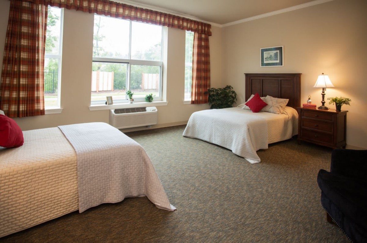 A spacious hotel room with two neatly made beds and a large window allowing natural light.