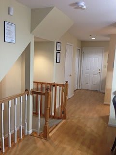 A well-lit hallway with wooden railings and multiple doors.