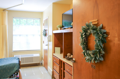 A warm and inviting interior of a room featuring wooden furniture, a decorative wreath, and natural light from the window.