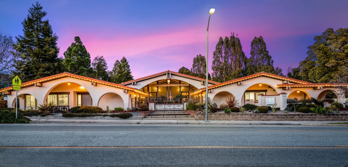 A well-lit restaurant building at sunset with a picturesque sky.