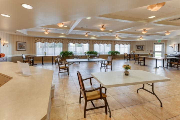 A spacious and well-lit room featuring tables and chairs, ideal for meetings or gatherings.