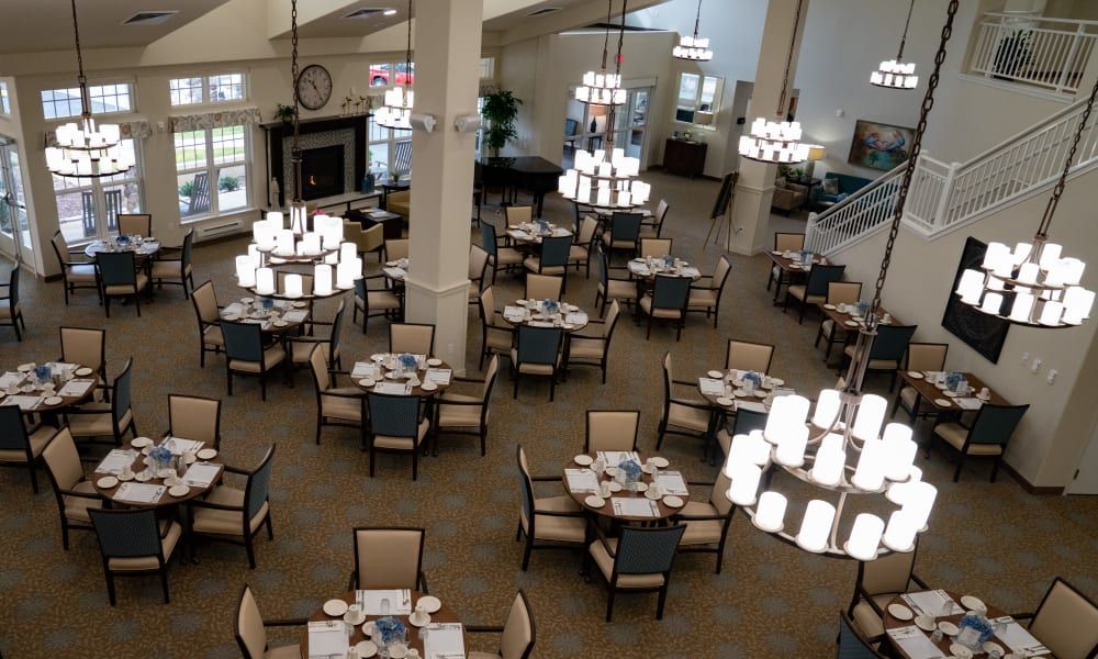 An elegant dining area with neatly arranged tables and chandeliers.