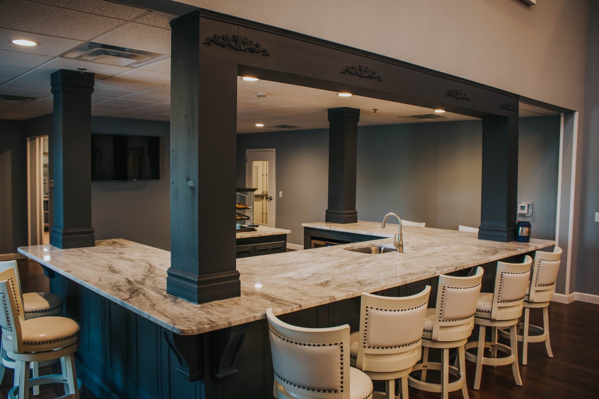 A stylish home bar with a marble countertop and cozy seating.