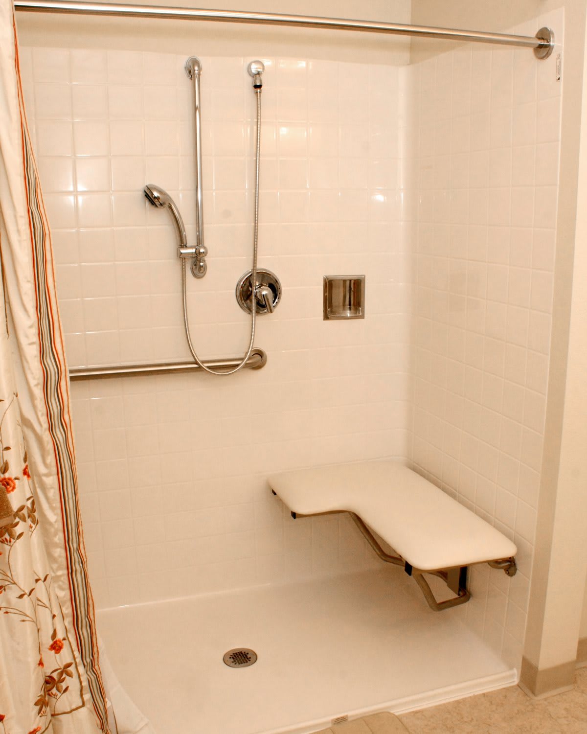 An accessible shower with a handheld showerhead and foldable seat.