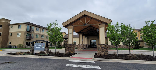 A welcoming entrance to a residential building, featuring a spacious porch and landscaped surroundings.