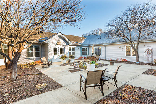 A peaceful residential courtyard with patio chairs and landscaping.