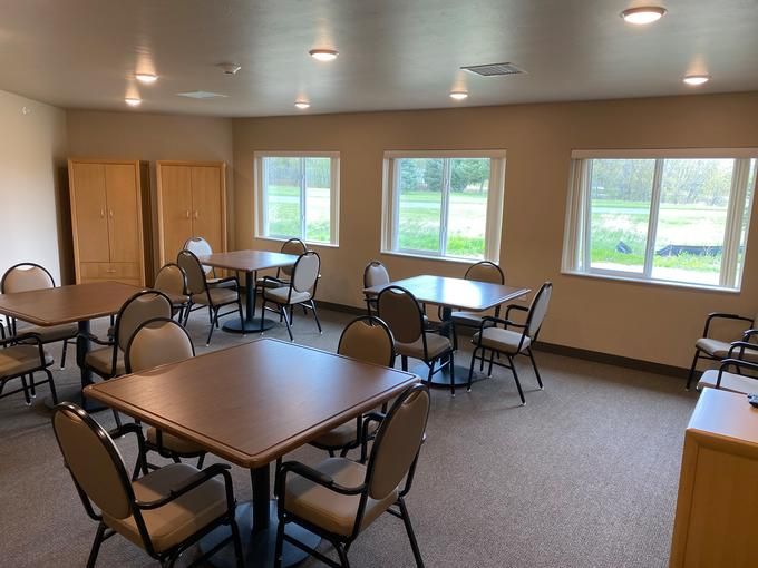 A well-lit meeting room with several tables and chairs arranged near large windows.